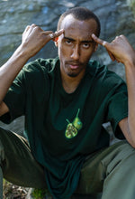 Load image into Gallery viewer, Man wearing oversized green DFKT Fruits t-shirt showing front graphic with silver rings