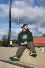 Load image into Gallery viewer, Man wearing oversized green tree of life hoodie with green roboflower cargos and forest green jordan 1s in skatepark
