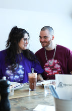 Load image into Gallery viewer, couple wearing oversized purple and red love bubbles valentines t-shirts while eating crepes and smiling