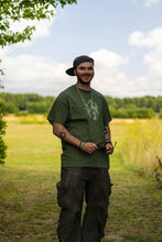 Load image into Gallery viewer, man smiling while wearing military green oversized magic mirror graphic t-shirt with green oversized roboflower cargos