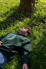 Load image into Gallery viewer, man wearing a green tree of life hoodie laying in grass