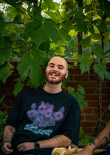 Load image into Gallery viewer, man wearing black oversized Plant A Seed floral graphic t-shirt while eating grapes