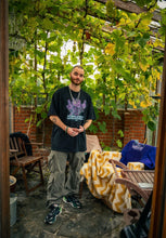 Load image into Gallery viewer, man wearing black oversized Plant A Seed floral graphic t-shirt with green oversized green roboflower cargos and puma rs-x shoes