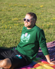 Load image into Gallery viewer, man wearing green misfit painted sweater with black misfit painted shorts and sunglasses while sunbathing