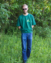 Load image into Gallery viewer, man wearing green oversized friends graphic tee with blue jeans