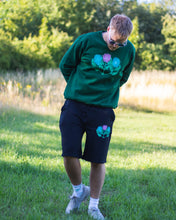Load image into Gallery viewer, man wearing green oversized misfit painted sweater with black misfit shorts and sunglasses
