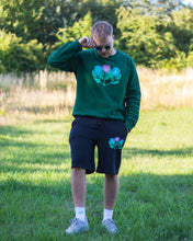 Load image into Gallery viewer, man wearing green oversized misfit painted sweater with black misfit shorts and sunglasses 2