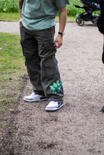 Load image into Gallery viewer, man wearing green oversized roboflower floral graphic cargos with jordan 3s