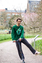 Load image into Gallery viewer, man wearing green oversized roboflower sweater while riding scooter