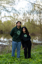 Load image into Gallery viewer, man wearing green oversized tree of life hoodie while hugging woman wearing a black oversized tree of life t-shirt