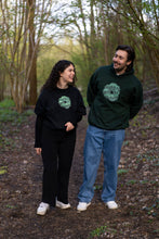 Load image into Gallery viewer, man wearing green oversized tree of life hoodie with woman wearing black oversized tree of life t-shirt while laughing and walking in the forest