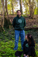 Load image into Gallery viewer, man wearing green oversized tree of life hoodie with woman wearing black tree of life t-shirt in the forest
