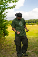 Load image into Gallery viewer, man wearing military green oversized magic mirror graphic t-shirt and oversized green roboflower cargos and green jordan 4's