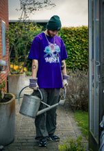 Load image into Gallery viewer, man wearing purple oversized misfit v2 graphic t-shirt with green roboflower cargos and green DFKT logo beanie with gardening equipment