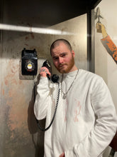 Load image into Gallery viewer, man wearing white thinker sweater with old vintage telephone in his hand