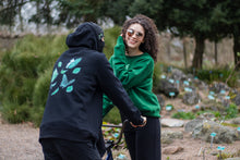 Load image into Gallery viewer, man with balaclava wearing black fly outside the jar oversized hoodie showing back graphic, woman wearing green oversized roboflower sweater