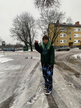 Load image into Gallery viewer, woman wearing green mindliquid graphic hoodie with lightning graphic pants