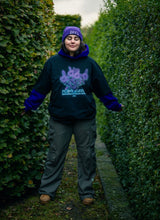 Load image into Gallery viewer, woman wearing layered, oversized black plant a seed graphic t-shirt with green roboflower cargos and purple DFKT logo beanie