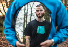 Load image into Gallery viewer, man wearing a black oversized panic control t-shirt looking into a mirror