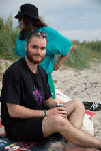 Load image into Gallery viewer, man wearing black euphoria graphic t-shirt at the beach with woman wearing oversized bright green no luck graphic t-shirt drinking a beer