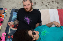 Load image into Gallery viewer, man wearing black euphoria graphic t-shirt at the beach with woman wearing oversized no luck graphic t-shirt