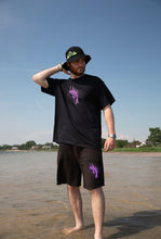 Load image into Gallery viewer, man wearing black oversized euphoria t-shirt and euphoria shorts at the beach