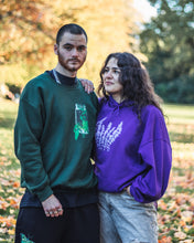 Load image into Gallery viewer, man wearing green oversized think outside the jar cozy sweater and black ripped butterfly sweatpants with woman wearing oversized purple lavender hoodie