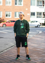 Load image into Gallery viewer, man wearing green oversized think outside the jar sweater and black think outside the jar shorts