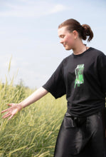 Load image into Gallery viewer, woman wearing black oversized think outside the jar graphic t-shirt in a field