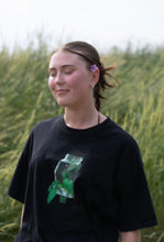 Load image into Gallery viewer, woman wearing black oversized think outside the jar graphic t-shirt with flower behind her ear