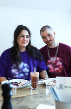 Load image into Gallery viewer, couple wearing oversized purple and red love bubbles valentines t-shirts while eating crepes