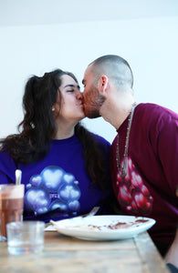 couple wearing oversized purple and red love bubbles valentines t-shirts while eating crepes and kissing