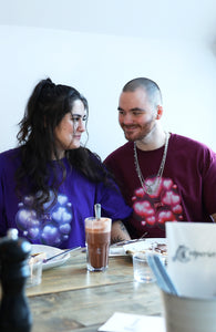 couple wearing oversized purple and red love bubbles valentines t-shirts while eating crepes and smiling