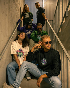 group of women and men wearing black roboflower v2 graphic sweater, white roboflower v3 t-shirt, green roboflower v3 sweater, purple roboflower onecolor graphic hoodie, black roboflower v2 t-shirt and green roboflower onecolor t-shirt in staircase