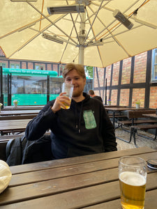 man drinking beer wearing black fly outside the jar graphic hoodie