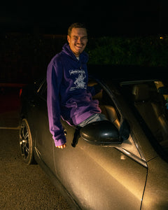 man hanging out of car with purple oversized onecolor hoodie