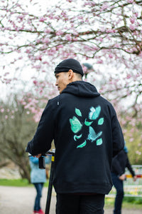 man wearing black Fly Outside the Jar Hoodie back butterfly graphic