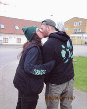 Load image into Gallery viewer, woman wearing a black growth longsleeve t-shirt kissing man with black fly outside the jar hoodie