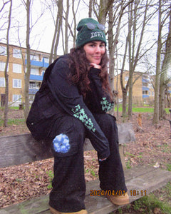 woman wearing black growth longsleeve with black bubbles cargos sitting on a bench
