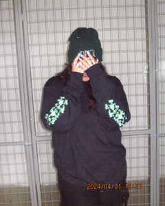 woman wearing black oversized growth longsleeve showing both sleeve graphics