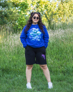 woman wearing blue oversized lifted living sweater with black euphoria shorts and sunglasses