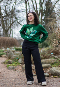 woman wearing green oversized roboflower sweater with black pants