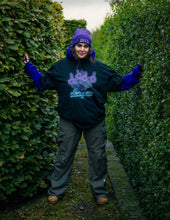 Load image into Gallery viewer, woman wearing layered, oversized black plant a seed t-shirt with green roboflower cargos and purple DFKT logo beanie