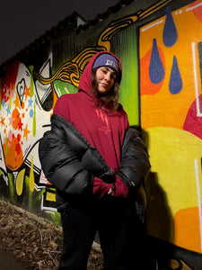 woman wearing red mindcontrol hoodie and purple DFKT logo beanie with black north face jacket