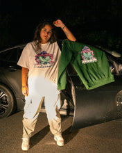 Load image into Gallery viewer, woman wearing white oversized roboflower v3 graphic t-shirt with green roboflower v3 sweater hanging over car door