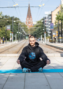 Man wearing Oversized Black Bubbles Graphic Hoodie with Blue shoes, meditating
