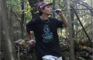 man wearing black mindliquid graphic t-shirt while drinking blue liquid