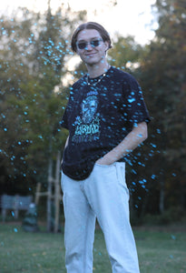 man wearing oversized black mindliquid graphic t-shirt while blue liquid is splashing