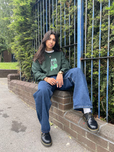 woman wearing oversized graphic think outside the jar sweater with blue jeans